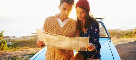 A couple looking at a map by their car.