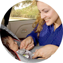 A mother putting baby in a car seat.