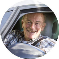 A senior smiling behind the wheel.