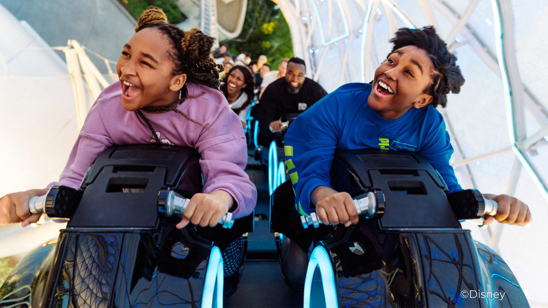 family happy excited riding roller coaster, older kids in front, parents in back seats
